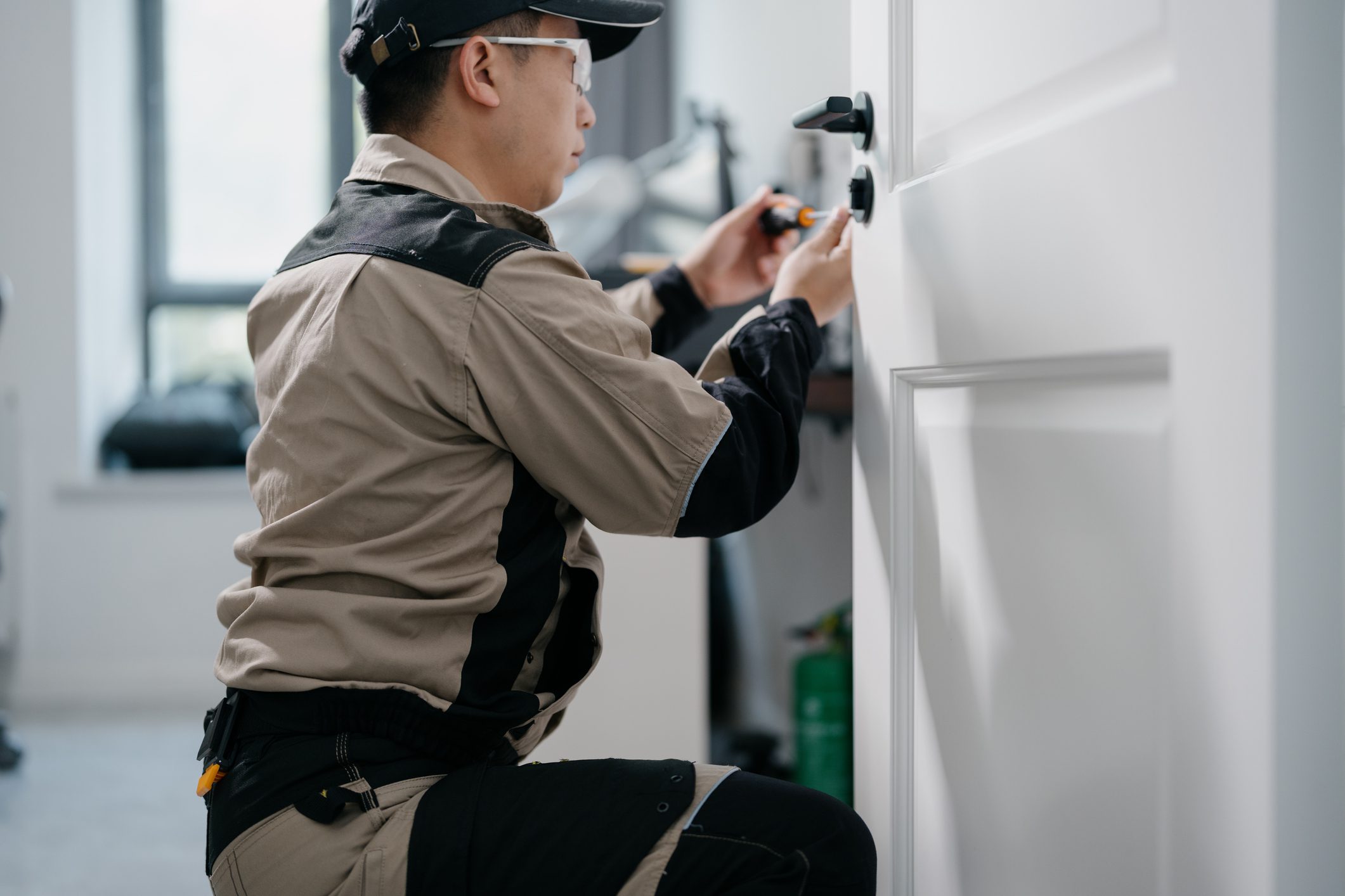The maintenance worker is repairing the door lock